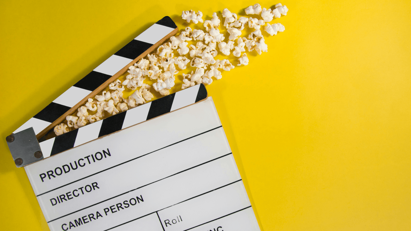 Filmklappe mit Popcorn vor gelbem Hintergrund