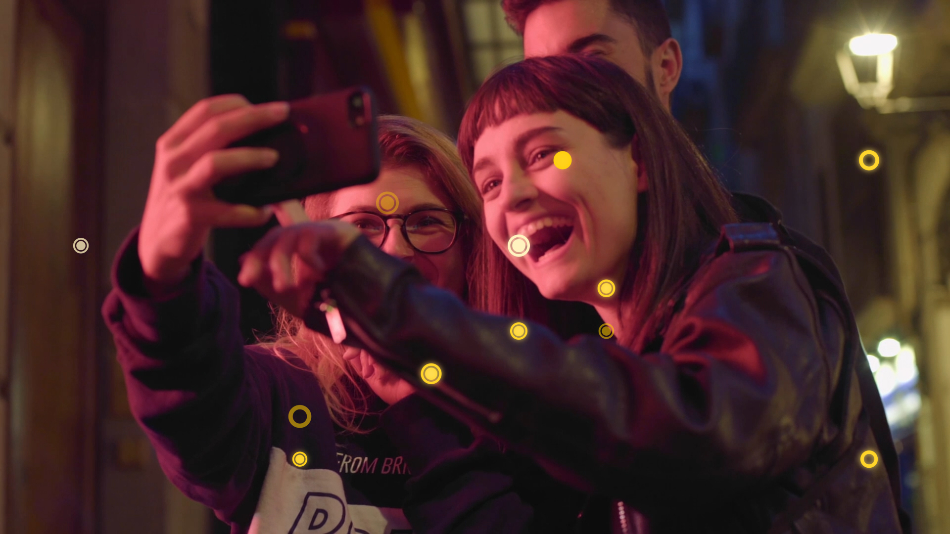 Eine Gruppe von drei Menschen schaut auf ein Smartphone